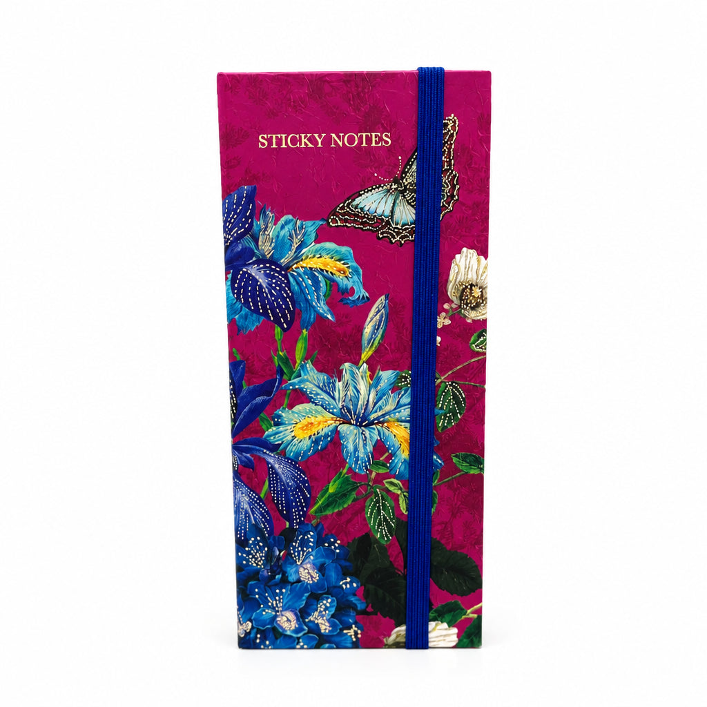 A vertical sticky notes notebook with a deep magenta cover decorated with blue, yellow, and white flowers, green leaves, and a butterfly. It features a blue elastic closure band and the words 'STICKY NOTES' printed near the top.