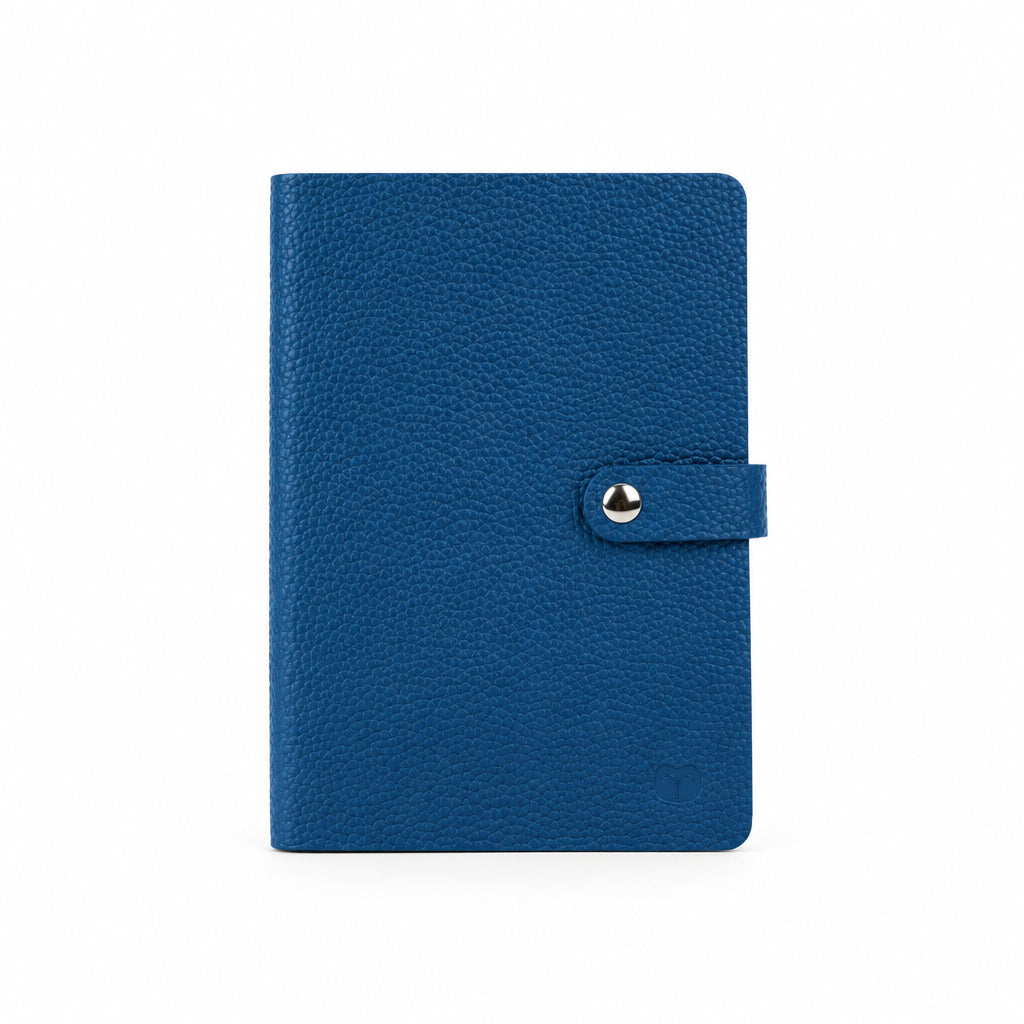 Blue A5 notebook with a textured cover and matching strap with a silver-tone snap-button closure, on a white background