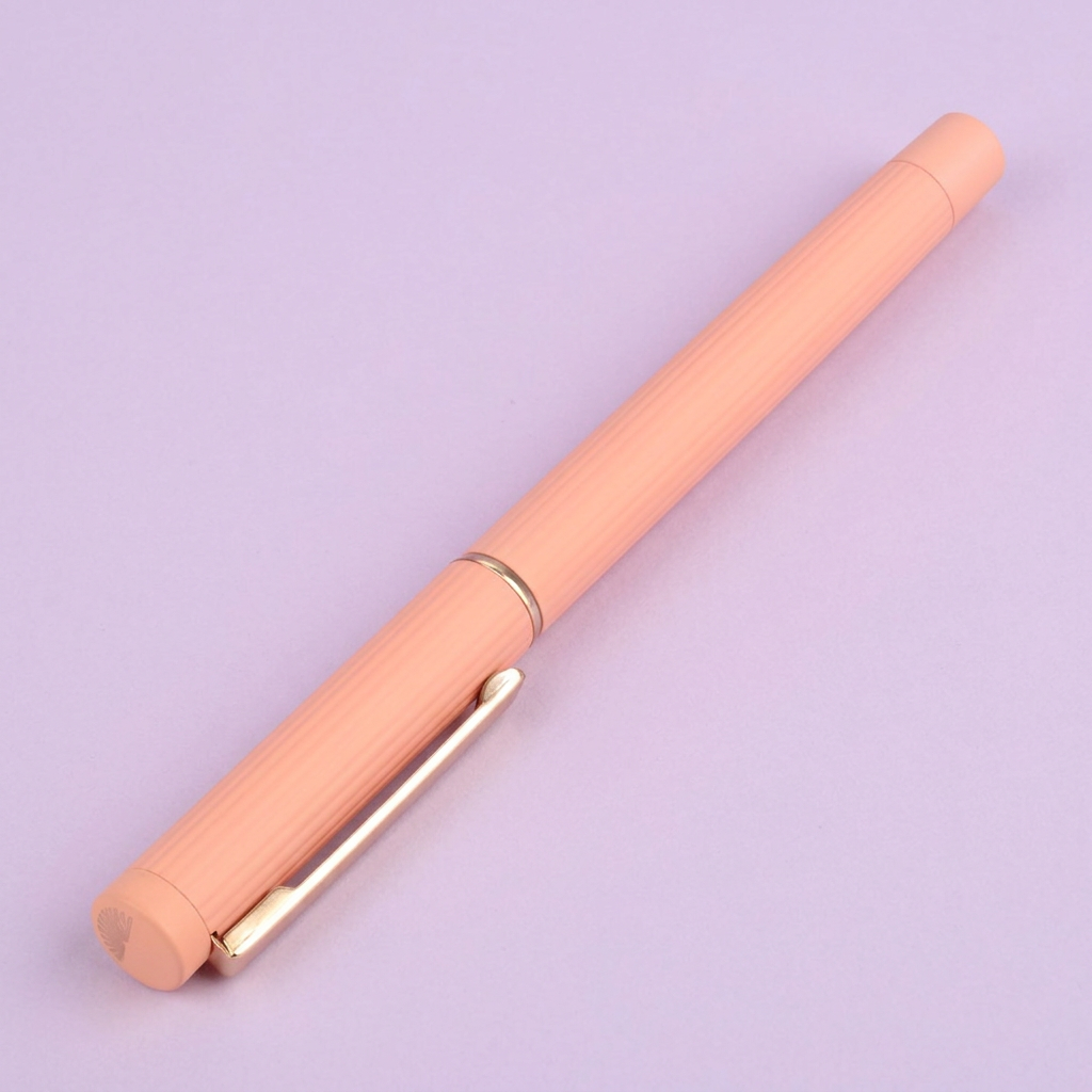 Peach pen with gold accents on a lilac background