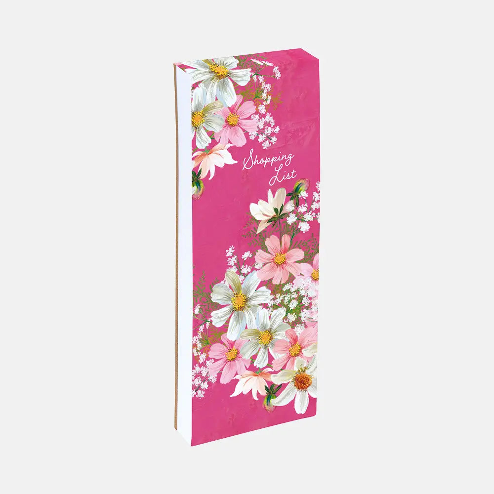 A pink shopping list notebook with a floral pattern of white and pink flowers, shown standing upright on a light gray background.