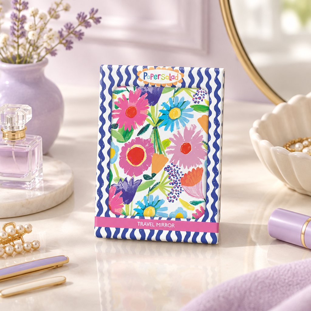Compact travel mirror with a colourful watercolour floral pattern and blue and white wavy borders, shown on a white background.