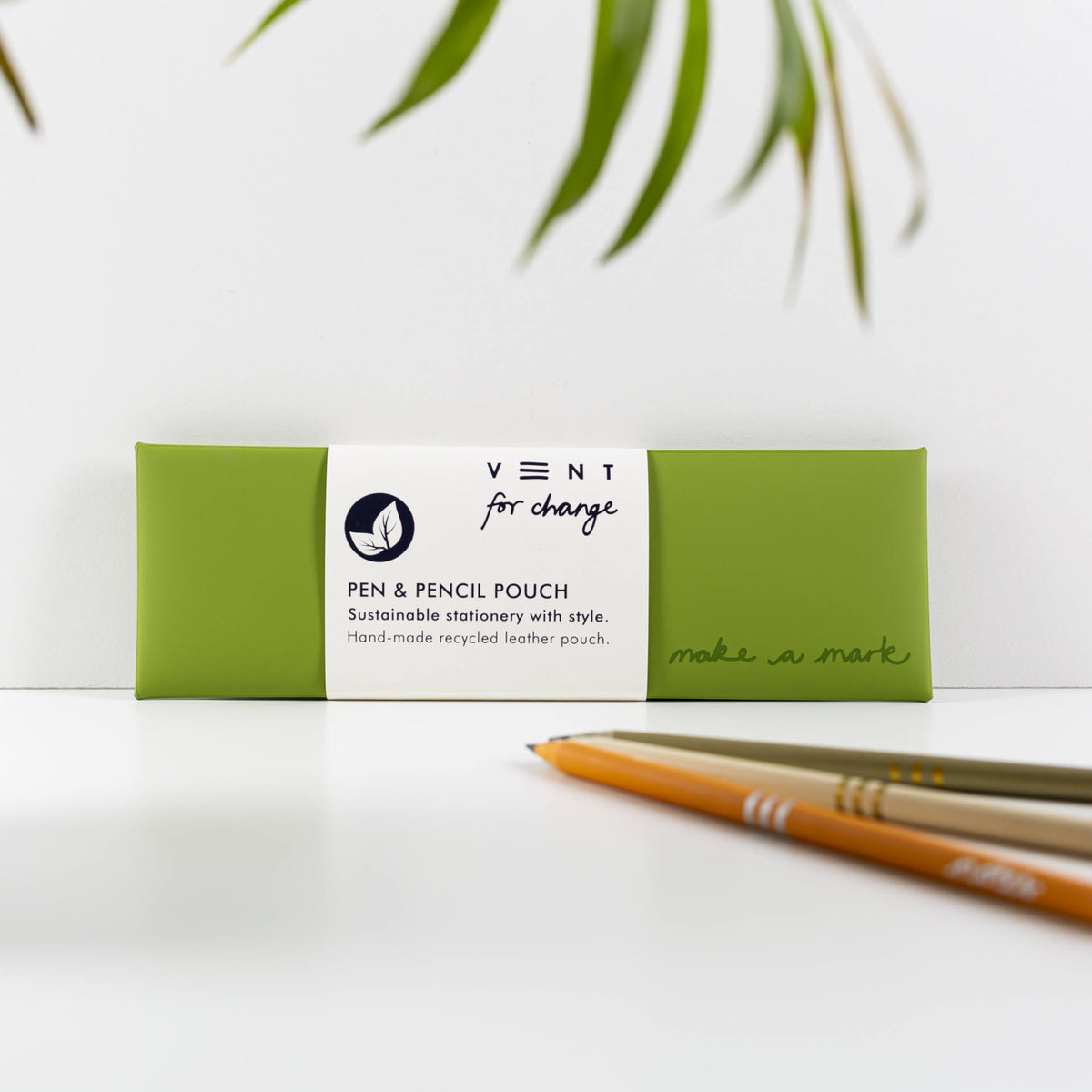 Green recycled leather pen and pencil case with a white paper sleeve, displayed beside pencils.