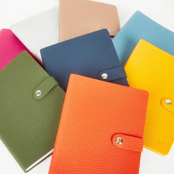Colourful textured notebooks arranged together, each with a matching button-tab closure