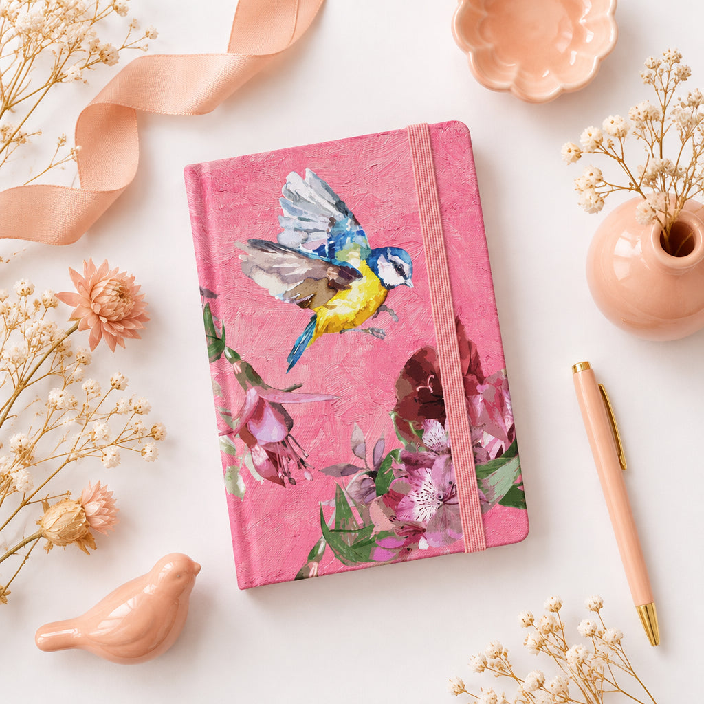 Pink notebook with bird and floral design on a white background