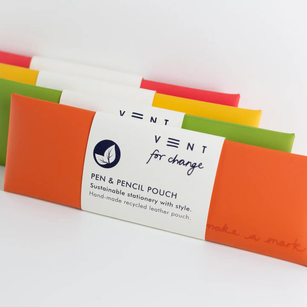 Close-up of orange, green, yellow and red leather pen and pencil pouches with a white paper label in the foreground.