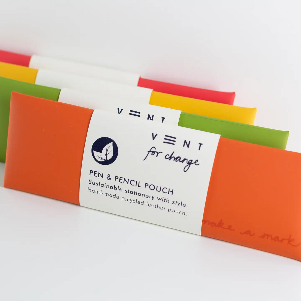 Close-up of orange, green, yellow and red leather pen and pencil pouches with a white paper label in the foreground.