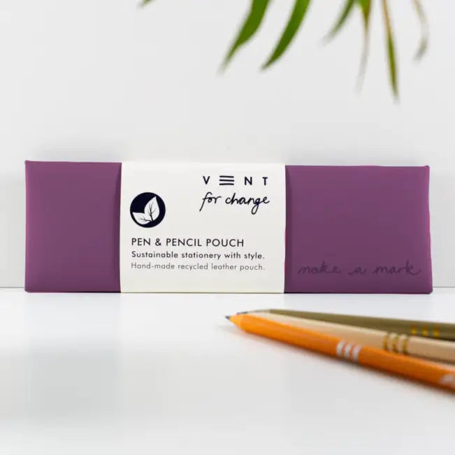 Purple recycled leather pen and pencil case with a white paper sleeve, displayed beside pencils