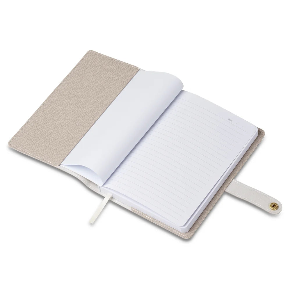 Open nude A5 notebook showing lined pages, a ribbon bookmark and snap-button strap closure, on a white background.