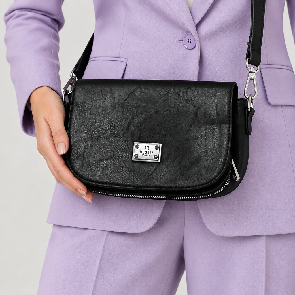 Black crossbody bag worn with a lilac suit.