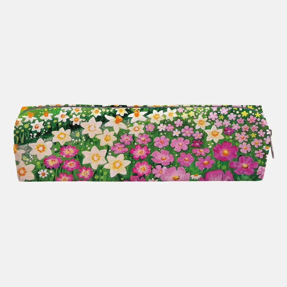 A rectangular zippered pencil case featuring a dense, colorful floral print with pink, white, yellow, and orange flowers on a green background, shown against a plain light gray studio backdrop.
