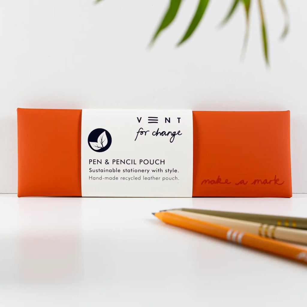 Orange recycled leather pen and pencil case with a white paper sleeve, displayed beside pencils.