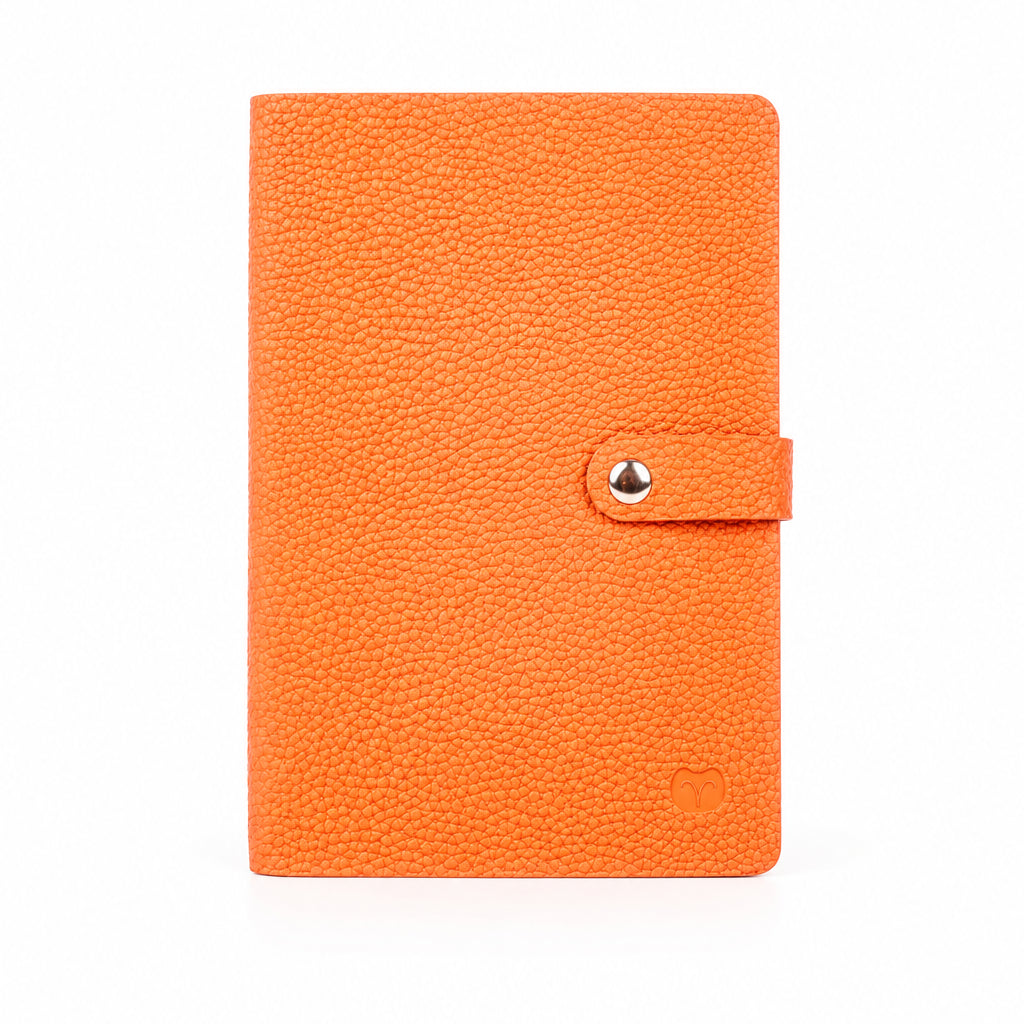 Orange A5 notebook with a textured cover and matching strap with a silver-tone snap-button closure, on a white background