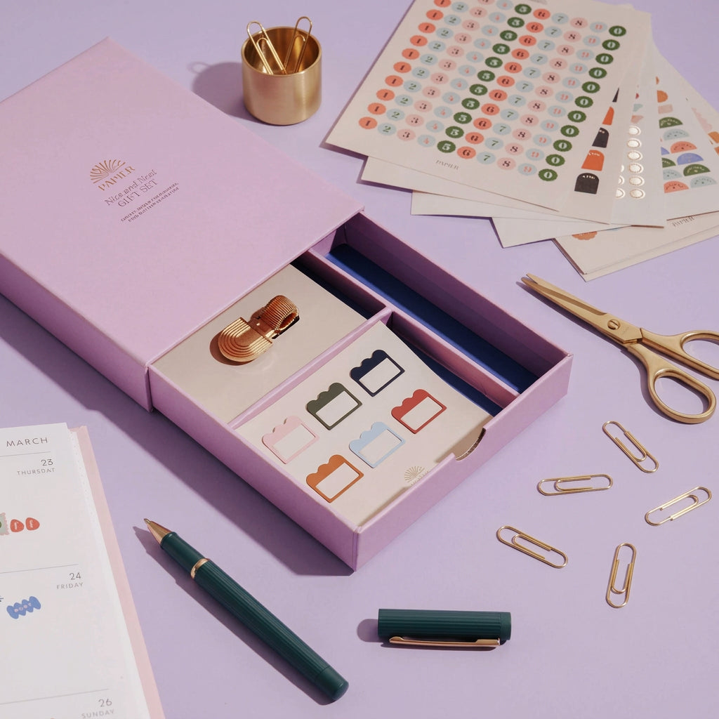lilac  stationery set box with a pen, stickers, and planner stickers on a lilc  surface.